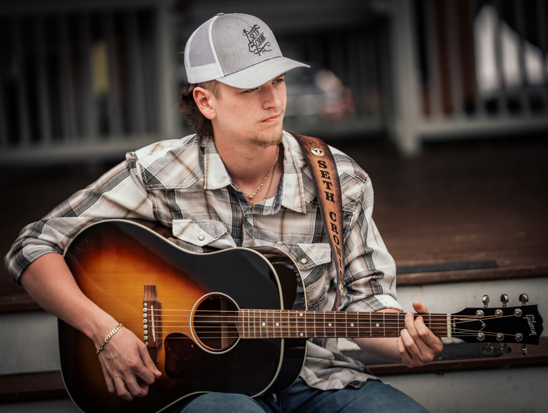 Seth Cronic seated with his sunburst acoustic guitar